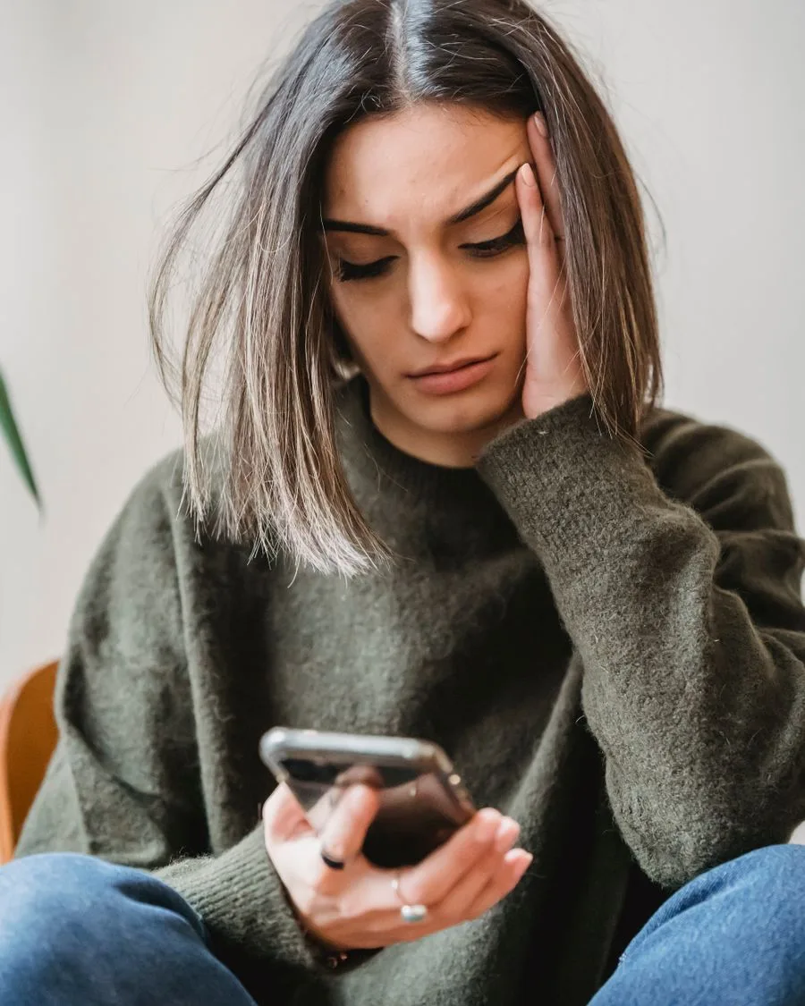 A concerned woman looking down at her smartphone