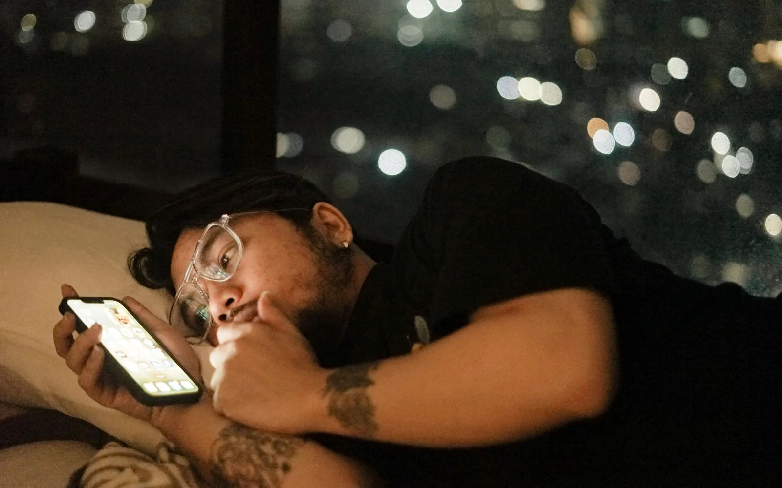 A man lying in bed and looking at a bright smartphone late at night