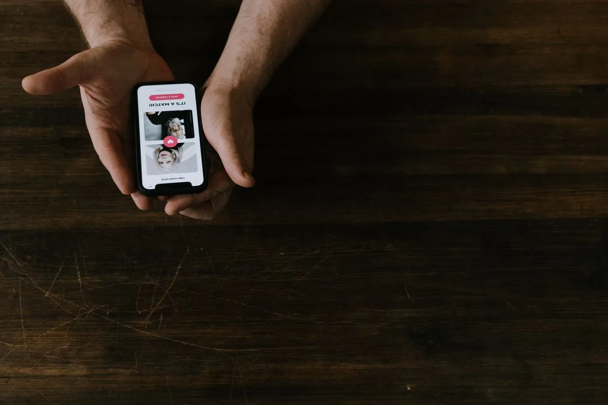 Hands holding a smartphone above a dark wooden table